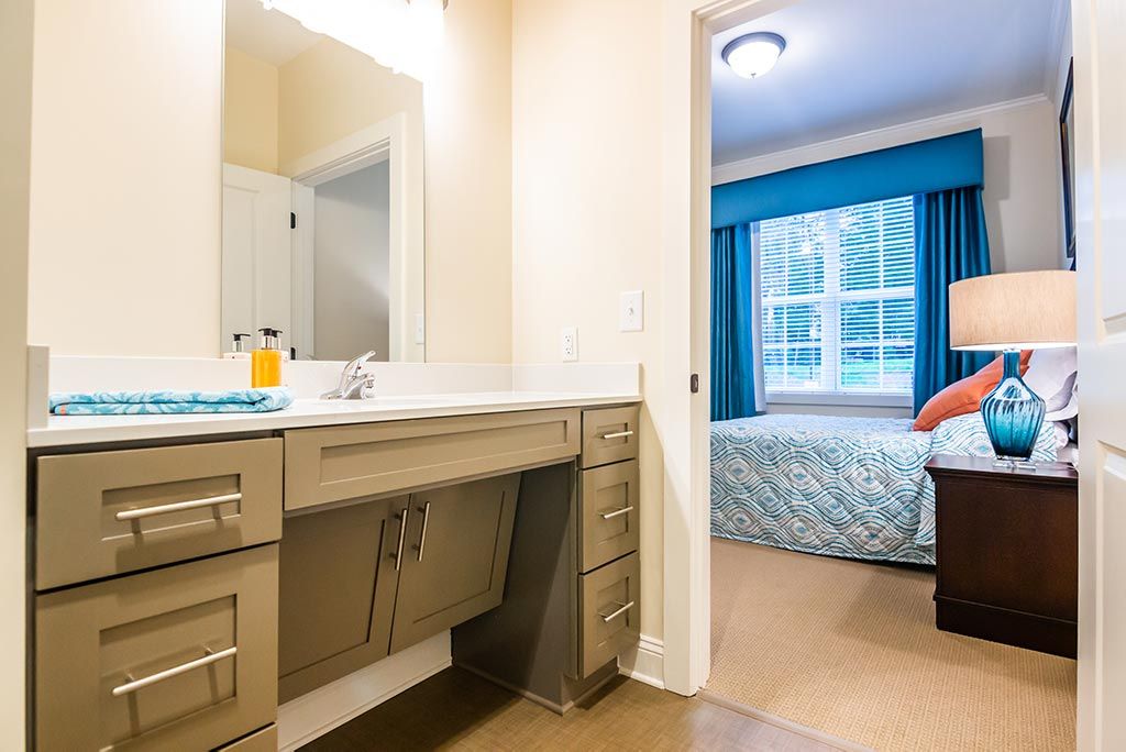 A modern bathroom with a view into a bedroom featuring bright blue curtains.