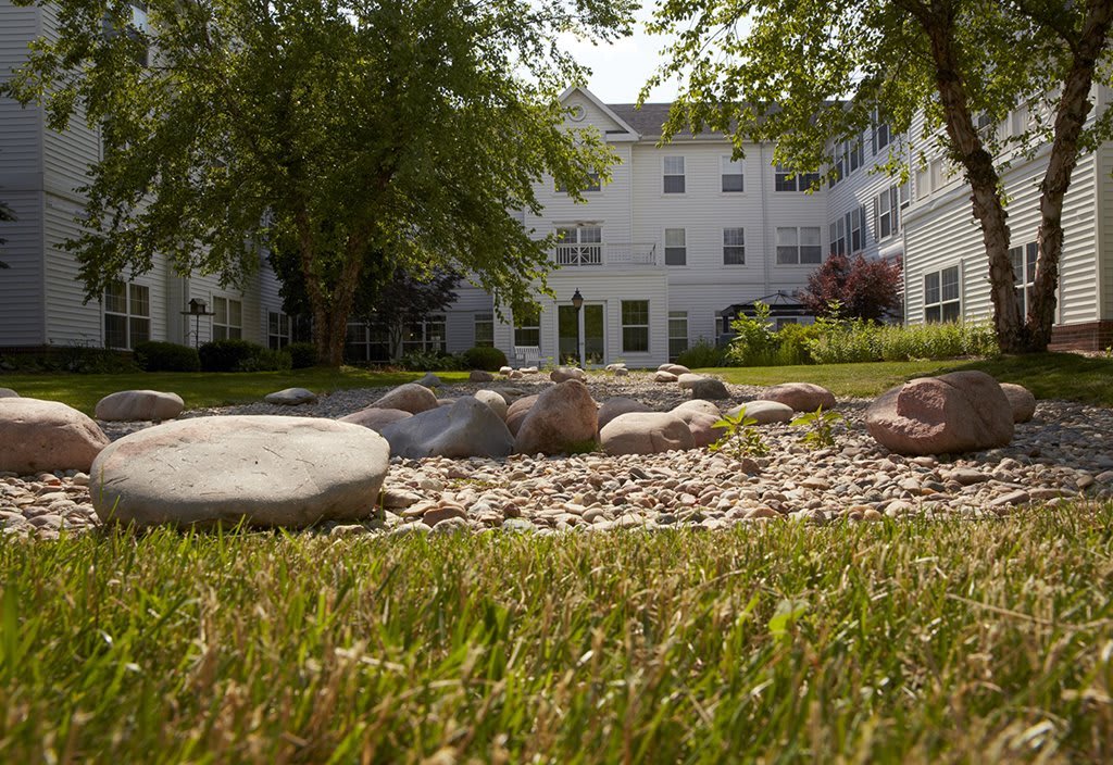 A landscaped garden with rocks and grass in front of a white building.