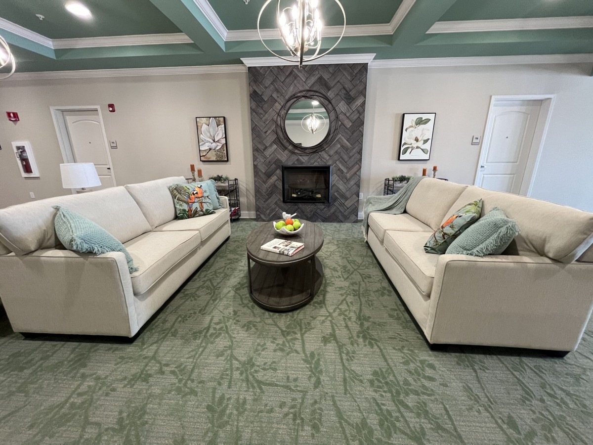 A modern living room with two beige sofas facing each other, a central coffee table, and a stylish fireplace.