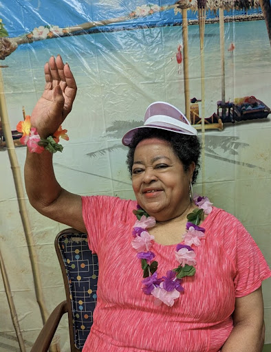 A joyful woman wearing a tropical hat and lei, celebrating in a festive atmosphere.