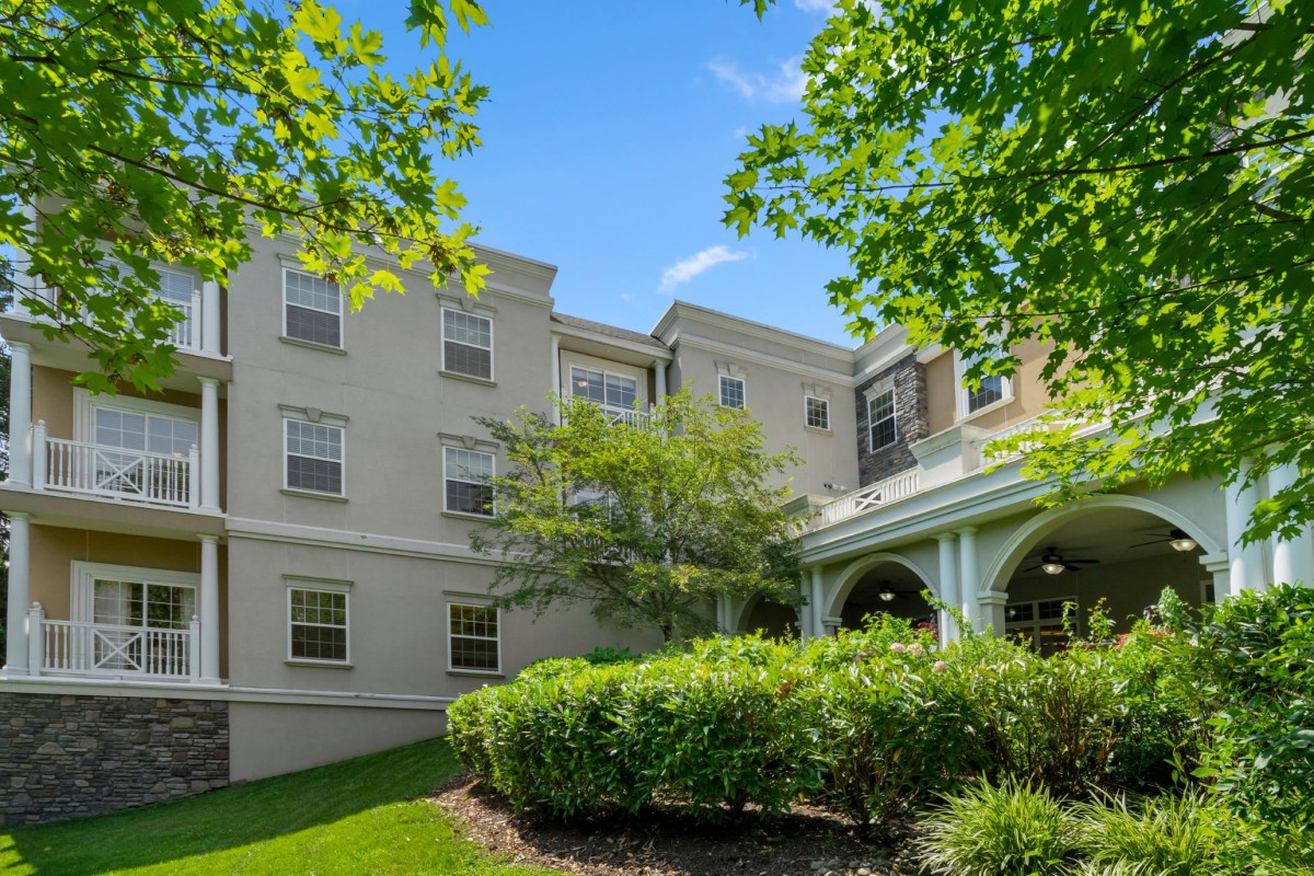 A residential building surrounded by trees and greenery on a clear day.