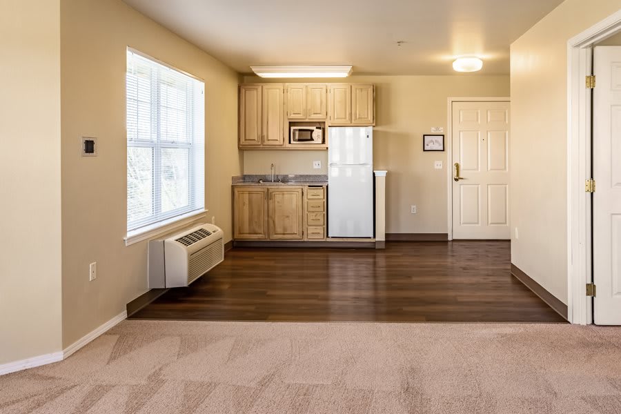 A minimalist apartment interior with a compact kitchen and hardwood flooring.