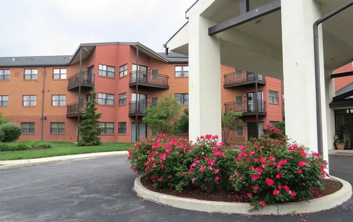 A residential building with balconies surrounded by landscaped gardens and blooming flowers.