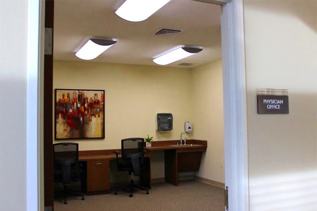 A modern office space with desks and chairs, adorned with artwork on the wall.