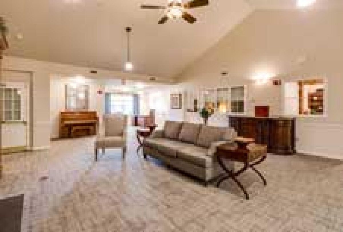 A spacious living room with a sofa, armchair, and ceiling fan, showcasing elegant interior design.
