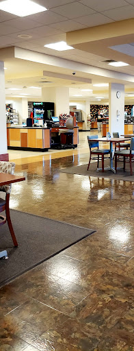 A spacious cafe interior featuring tables and chairs, a counter in the background, and polished floors.
