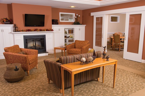 A cozy living room with a fireplace, comfortable seating, and warm-toned decor.