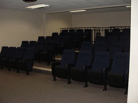 An empty auditorium with multiple rows of theater seating.