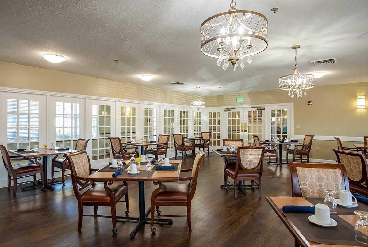 An elegant dining room with chandeliers and neatly arranged tables and chairs.