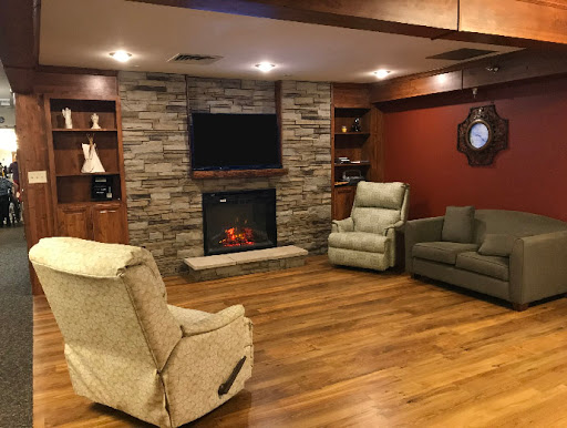 A cozy living room featuring a stone fireplace, comfortable seating, and warm wooden flooring.