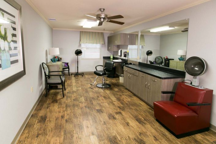 A spacious hair salon interior with wooden flooring, chairs, and large mirrors.
