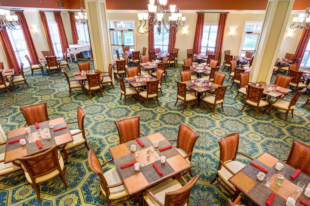 A spacious and elegantly decorated dining room with neatly arranged tables and chairs on a patterned carpet.