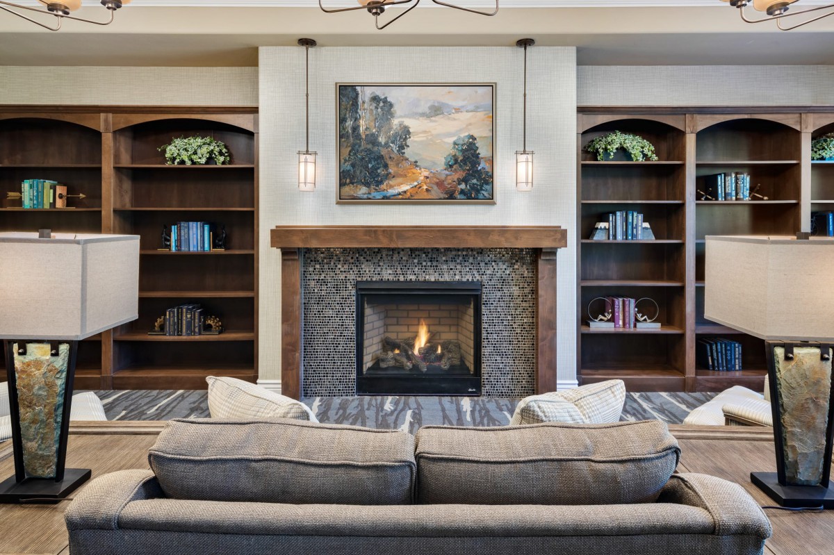A cozy living room with a central fireplace, surrounded by built-in bookshelves and a comfortable couch.