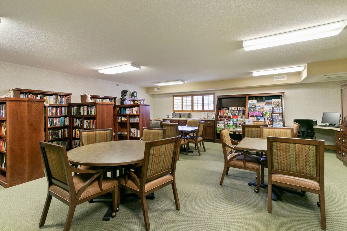 A cozy library reading area with tables, chairs, and bookshelves.