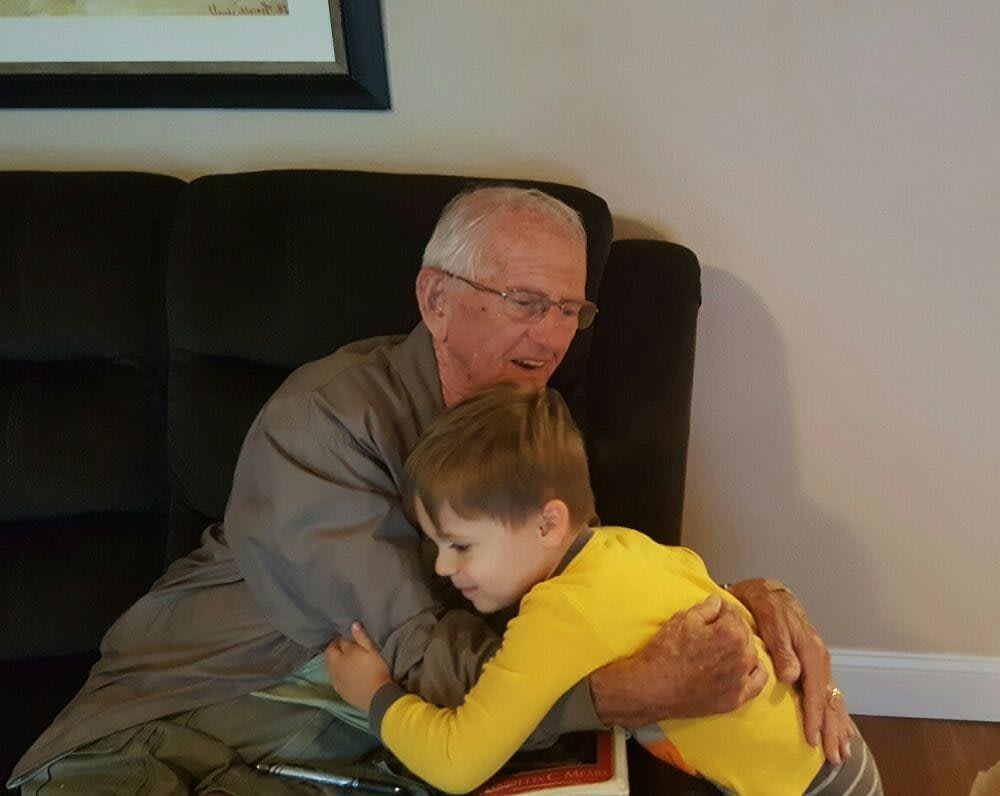 A warm moment between a grandparent and a child sharing a hug on the couch.