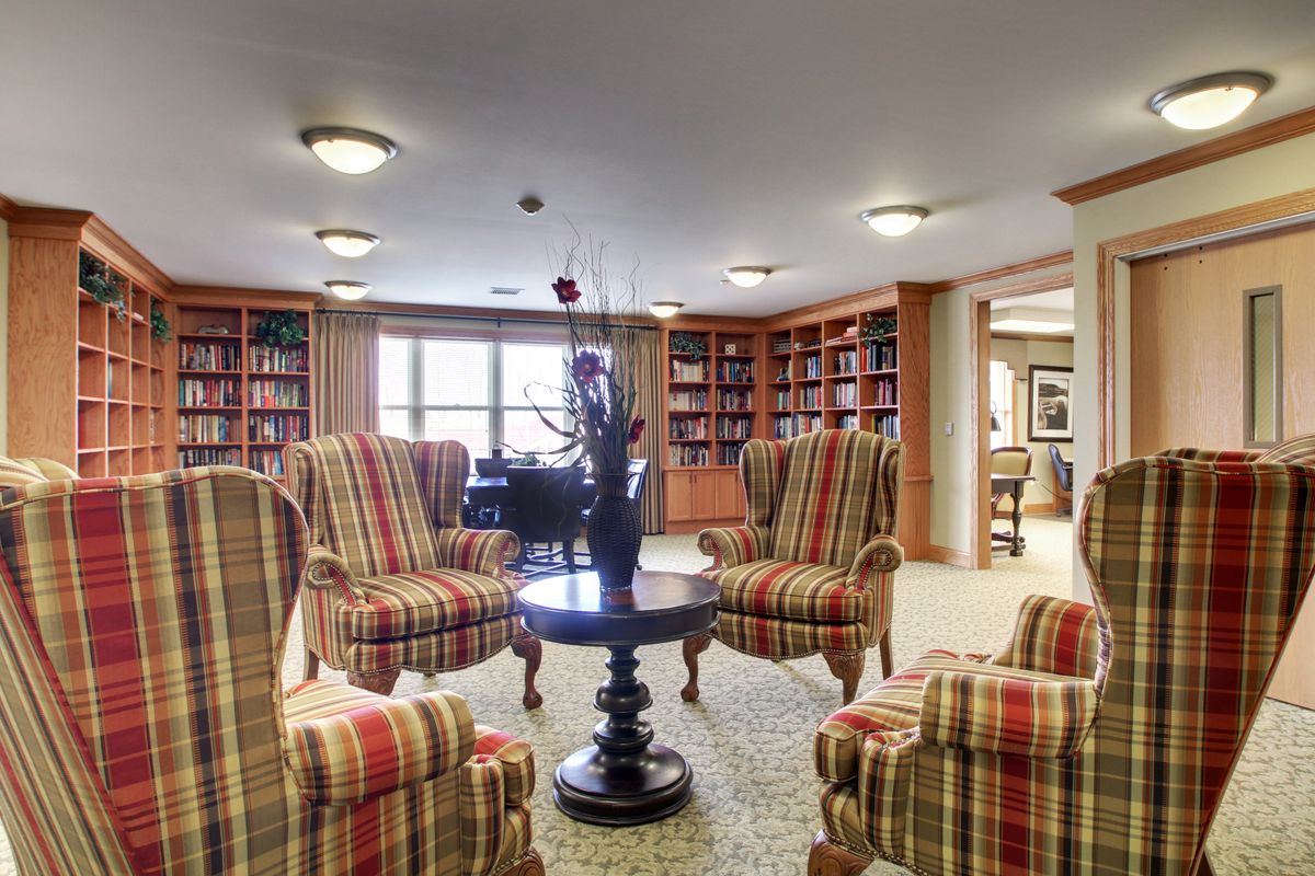 A cozy library lounge with armchairs and bookshelves.