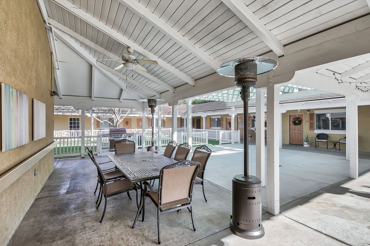 A covered outdoor patio with a dining table, chairs, and a heater.