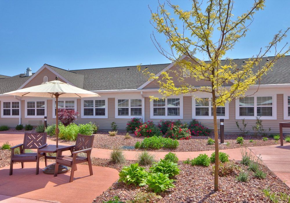 A beautifully landscaped patio area with outdoor seating in front of a house.