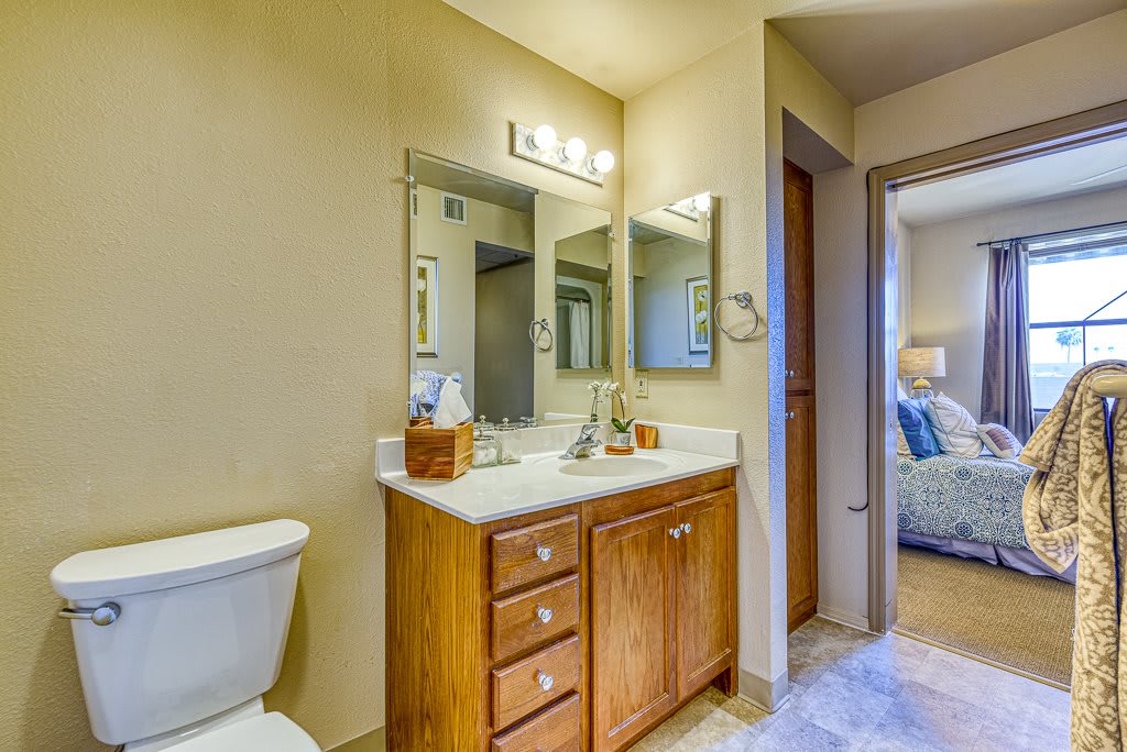 A well-lit bathroom with a wooden vanity, two mirrors, and a toilet.