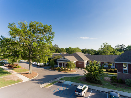 A tranquil residential building surrounded by greenery and a clear blue sky.