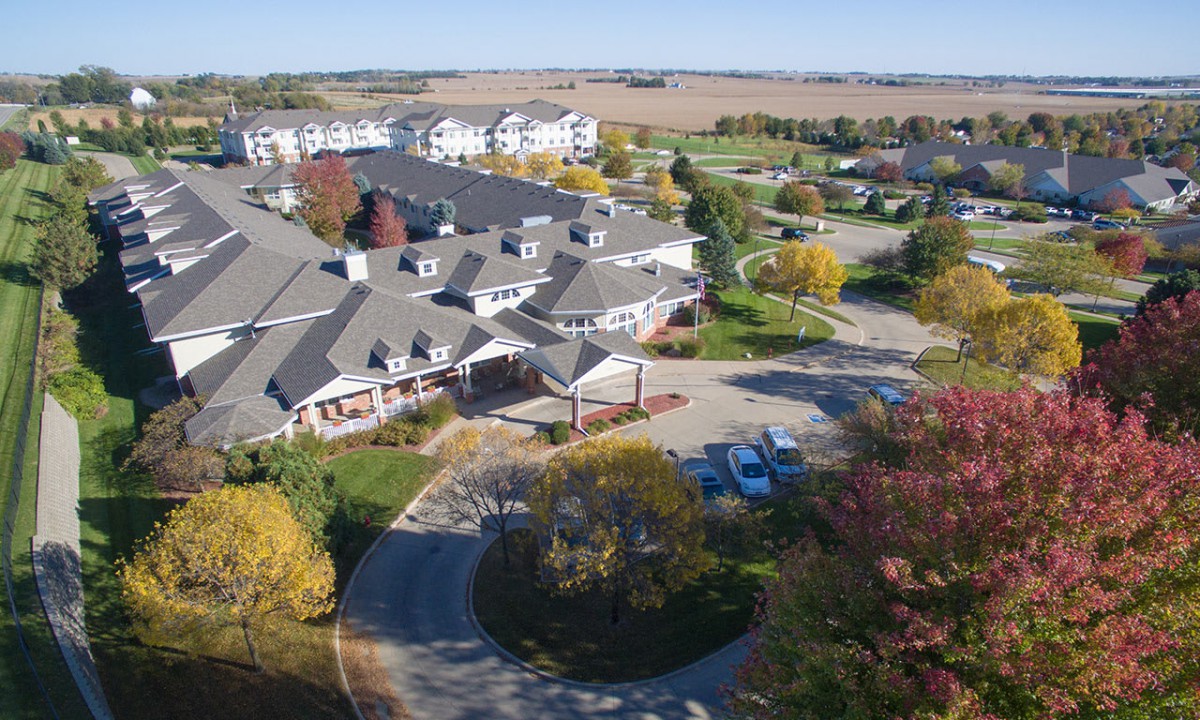 Aerial view of a suburban residential area with buildings surrounded by autumn trees and roads.