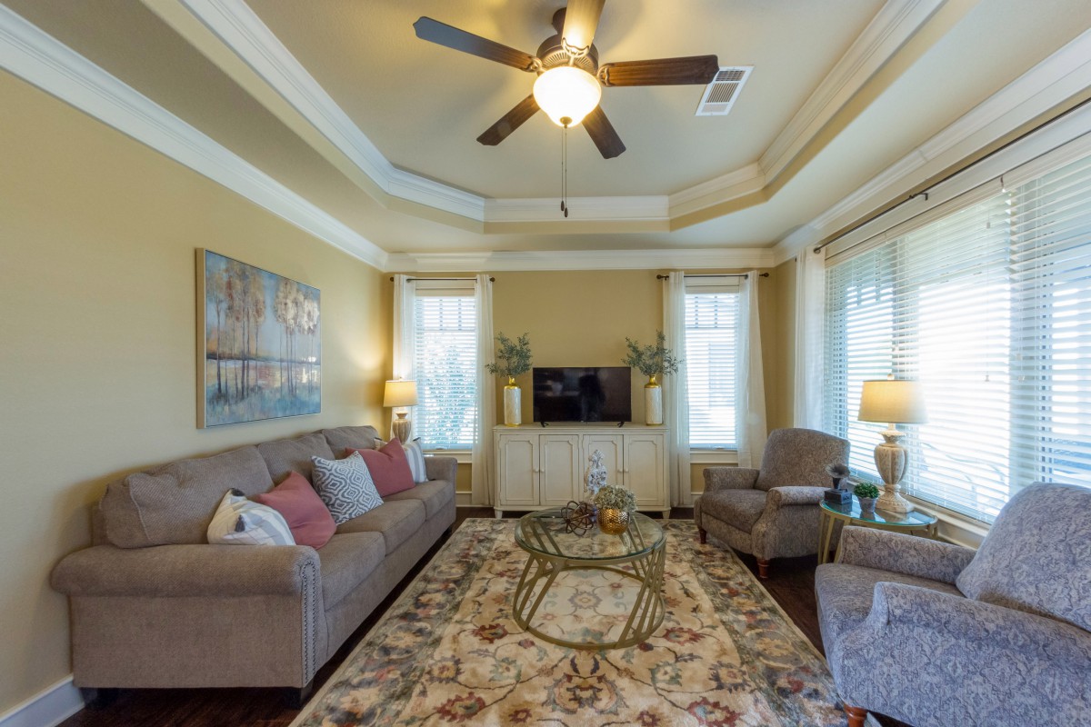 A cozy living room with a sofa, armchairs, and a large rug, featuring warm lighting and decorative elements.
