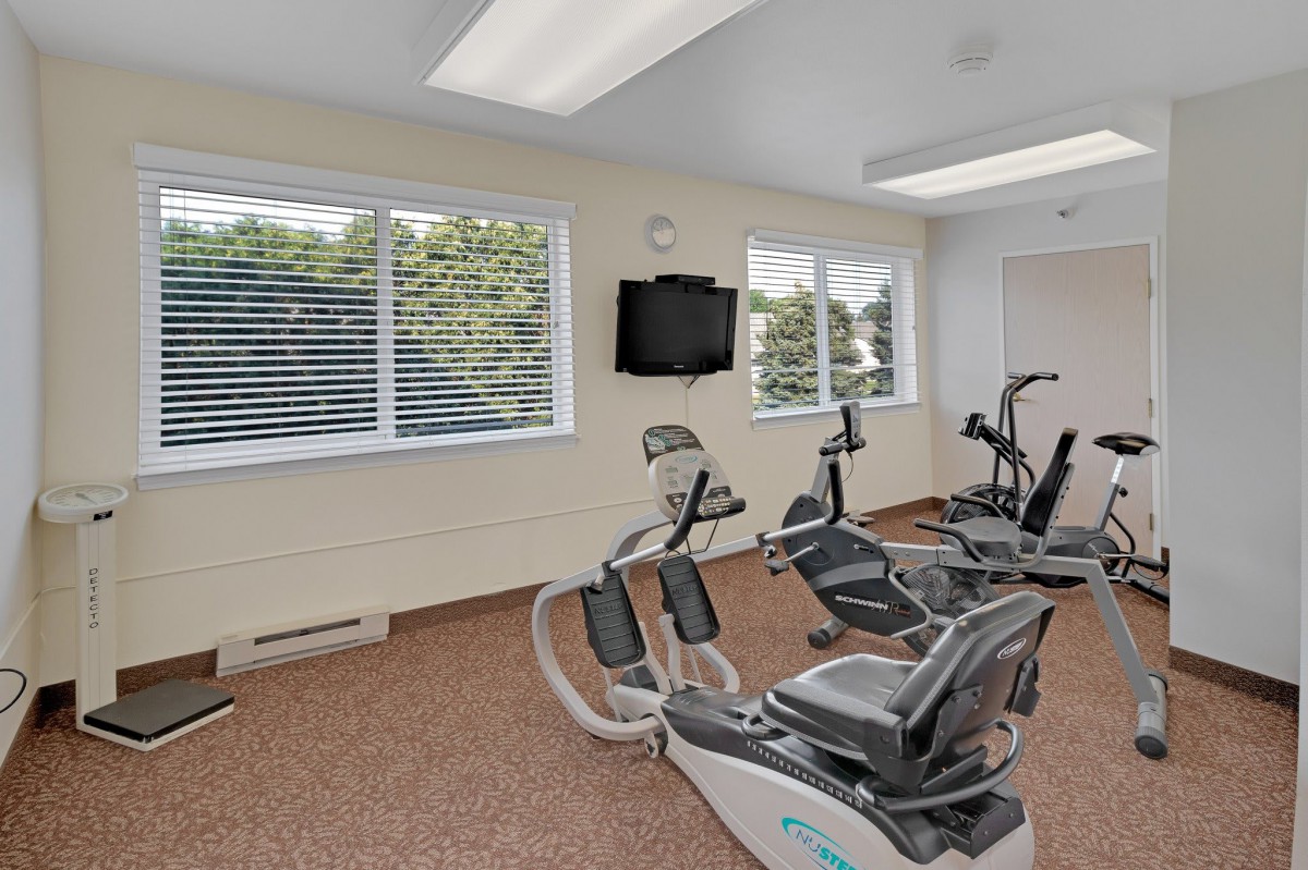 A small gym room with stationary bikes and a wall-mounted television.