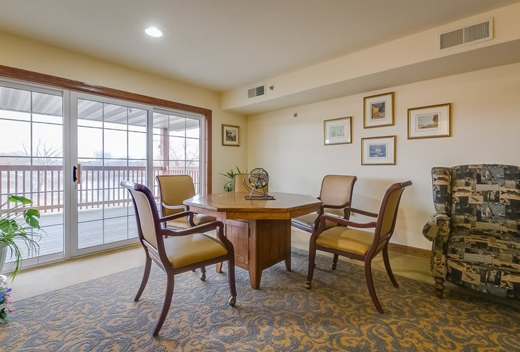 A cozy meeting room with a wooden table, four chairs, and decor on the walls.
