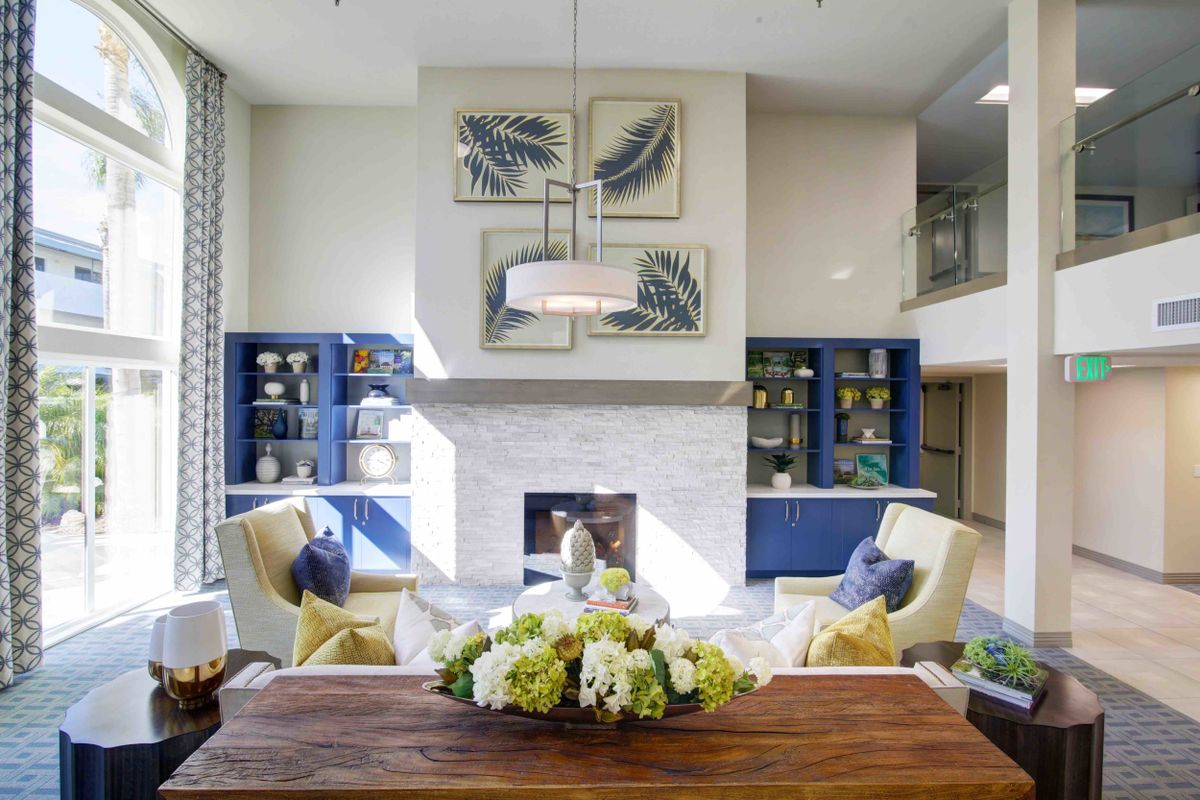 A modern living room with a stylish fireplace, comfortable seating, and elegant decor featuring artwork and a floral arrangement.