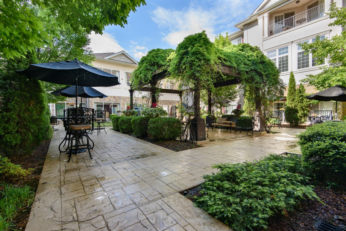A beautifully landscaped patio area with a pergola, outdoor furniture, and lush greenery.