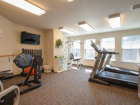 A well-lit gym room with treadmills and other exercise equipment.