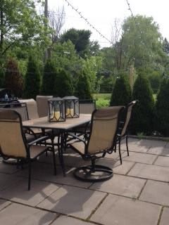 A cozy outdoor patio with a table and chairs surrounded by greenery.