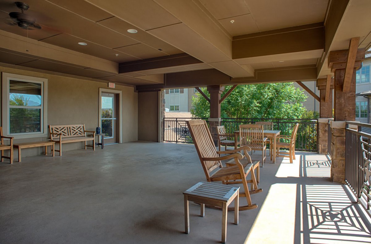 A spacious covered patio with wooden rocking chairs and benches, providing a comfortable outdoor seating area.