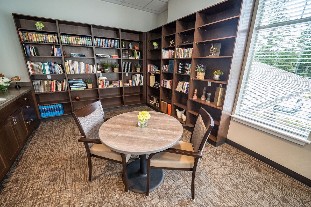 A cozy library reading area with bookshelves and a round table.