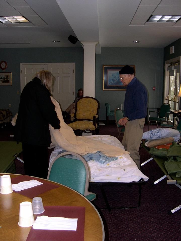 Two people arranging bedding in a room.