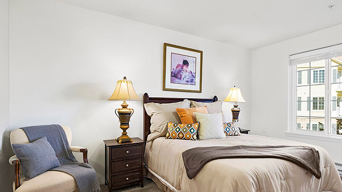 A cozy bedroom with elegant lamps and decorative pillows.