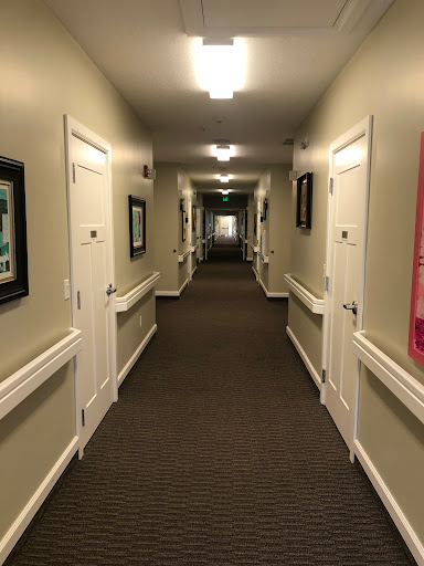 A well-lit hallway featuring multiple doors and framed pictures along the walls.