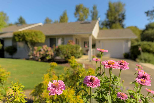 A charming house surrounded by vibrant flowers, showcasing a beautiful garden on a sunny day.