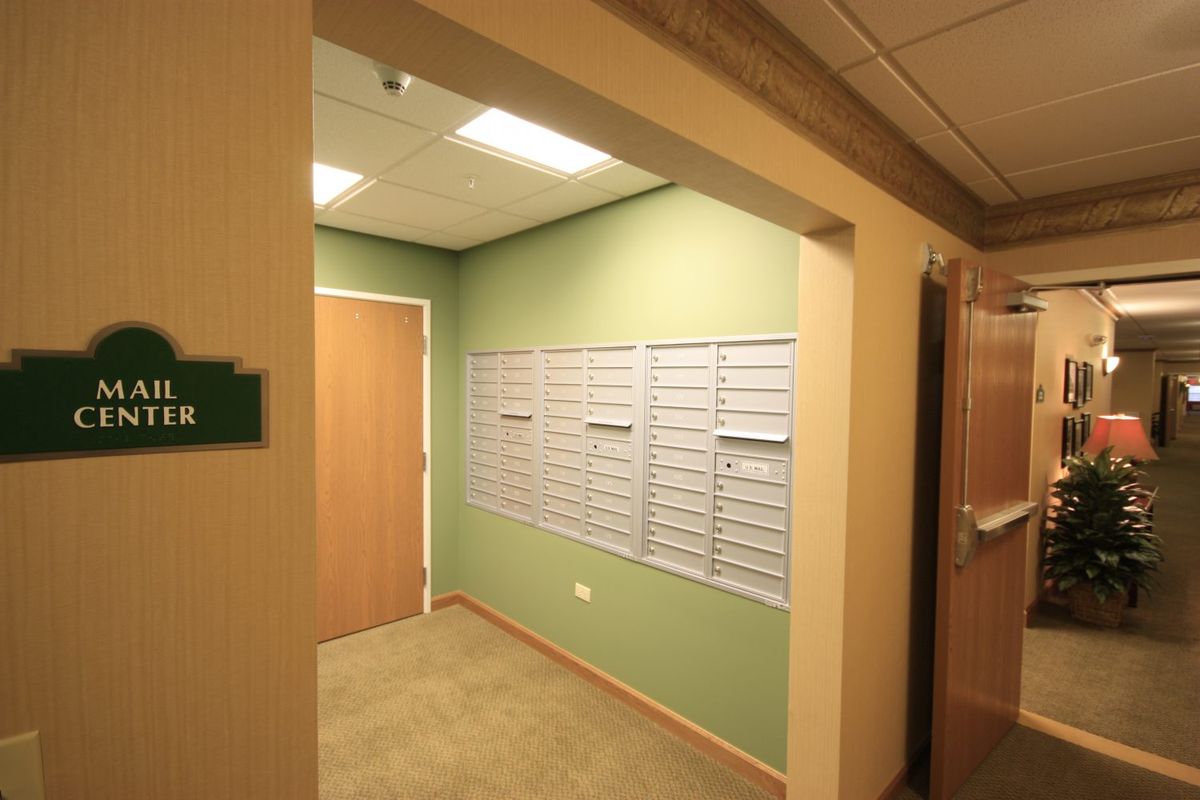 A hallway with a row of mailboxes on a green wall in an office building.