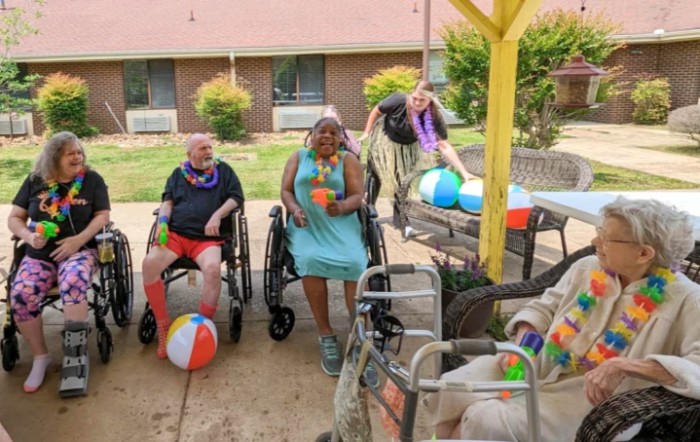 Seniors enjoying an outdoor social gathering with beach balls and leis.