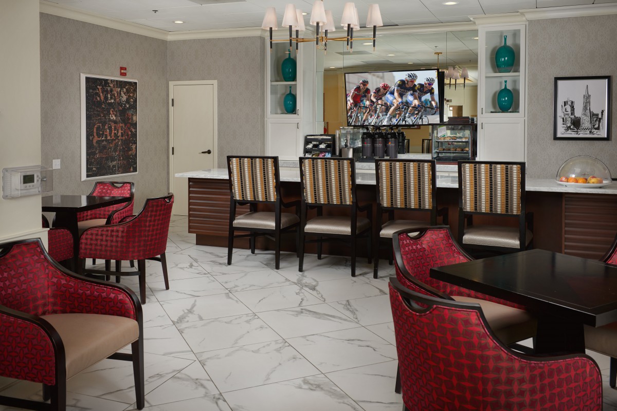 A modern dining area with upholstered chairs, a bar counter, and a television.