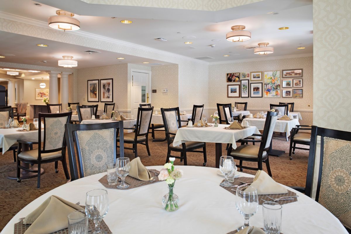 Elegantly set dining room with multiple tables and chairs, showcasing tasteful decor and cozy ambiance.