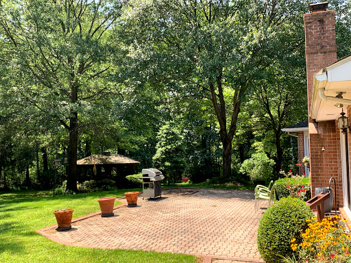 A serene outdoor space featuring a patio surrounded by lush greenery and flower pots, perfect for relaxation and gatherings.