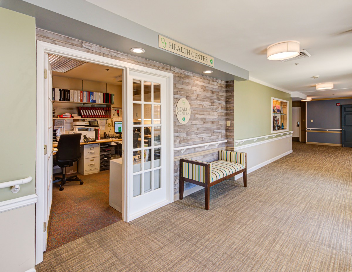 A well-organized reception area with a view into an office, featuring a hallway and a waiting bench.