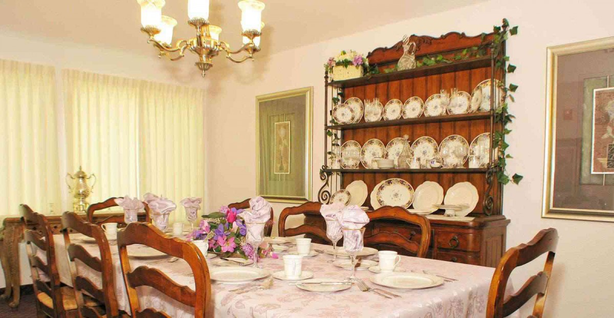 An elegant dining room with a table set for a meal, featuring a china cabinet and chandelier.