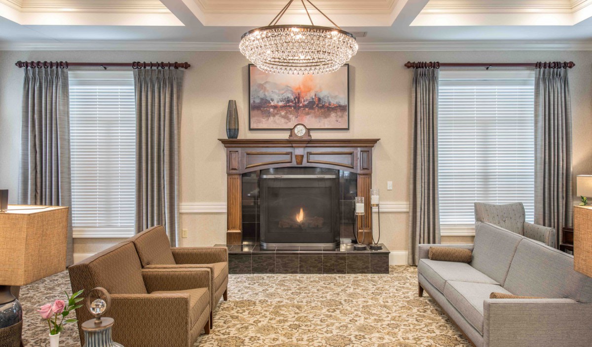 A luxurious living room featuring a central fireplace, elegant chandelier, and tasteful artwork.