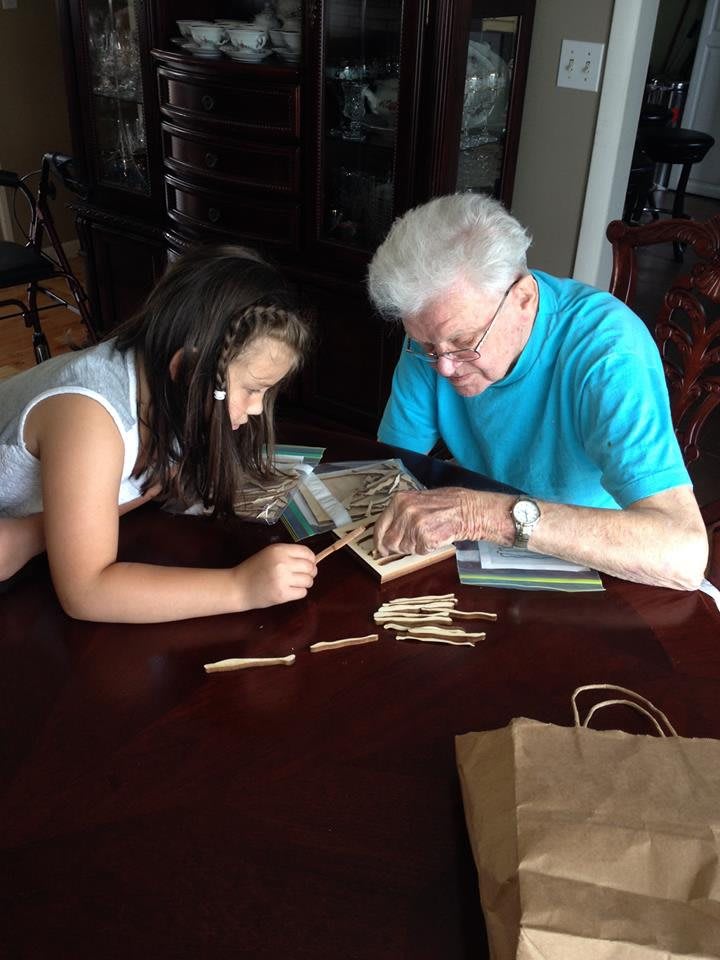An elderly person and a child engaging in a crafting activity together at a table.