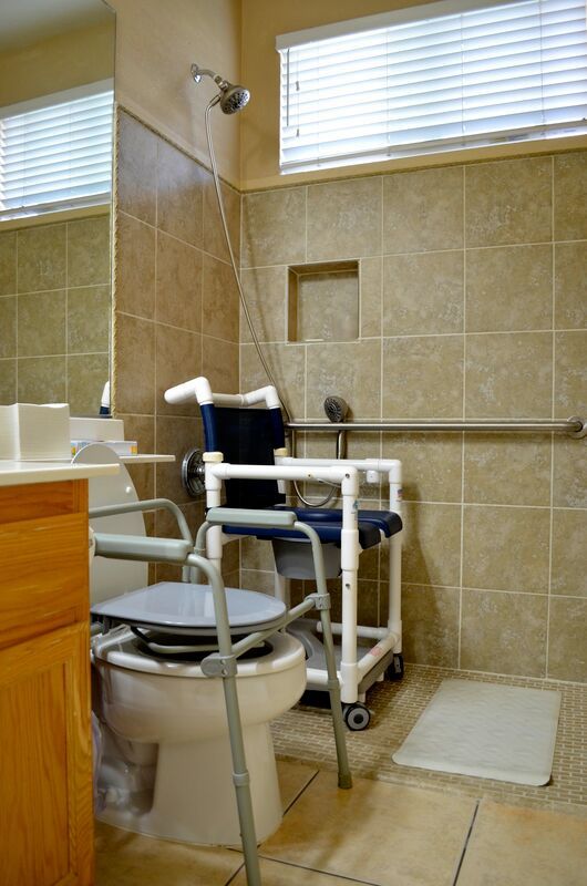 An accessible bathroom equipped with a mobility aid wheelchair, grab bars, and tiled walls.