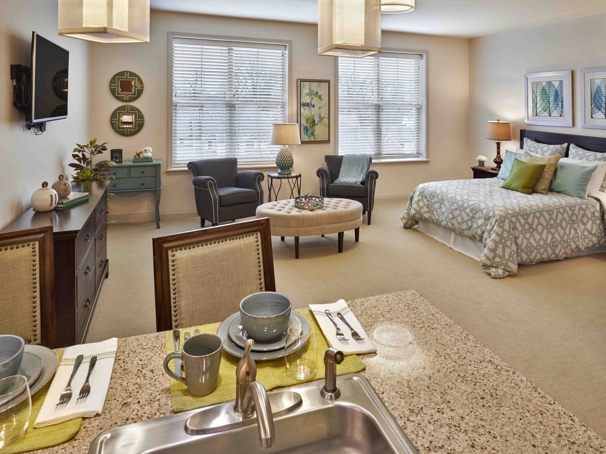 A modern studio apartment featuring a cozy living area and a kitchenette with elegant furnishings.
