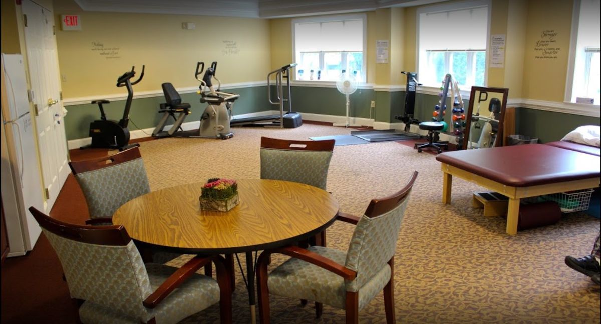 A fitness room featuring various exercise equipment and a seating area with a table and chairs.